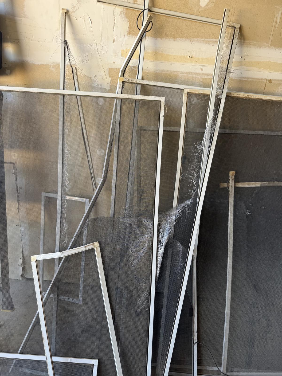 Torn sun-damaged window screens before re-meshing