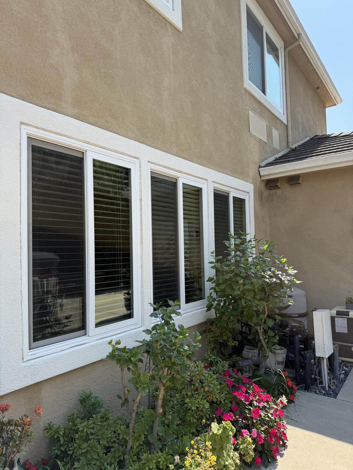 Row of clean exterior windows on a stucco two-story home after service
