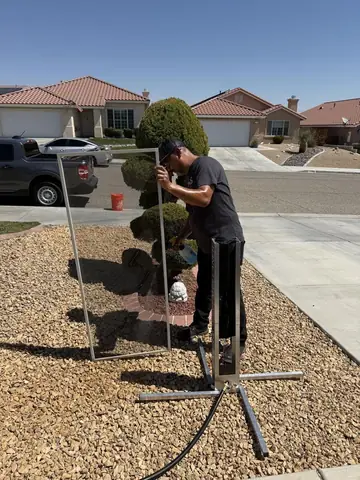 Window screen being washed on a stand in a front yard in Phelan