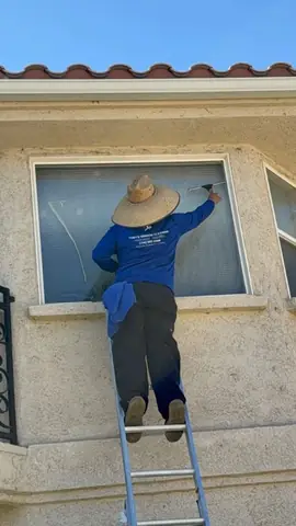 Squeegeeing a second story window from a ladder in Spring Valley Lake